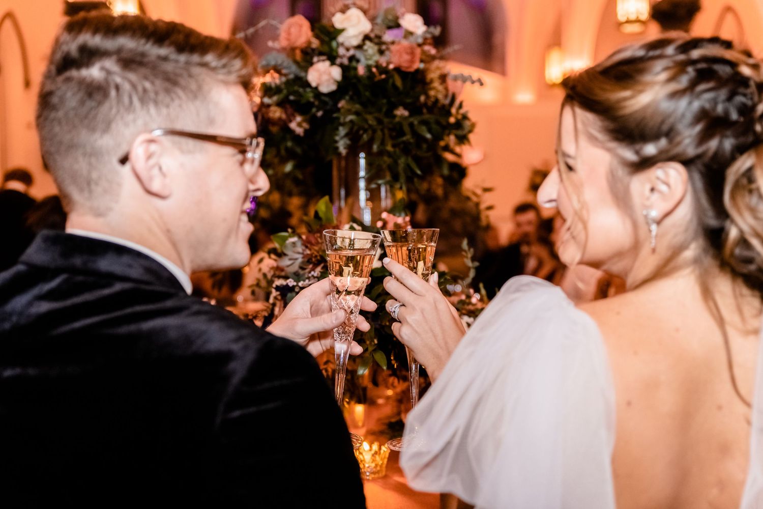 Intimate moment captured at an indoor reception with warm orange lighting.