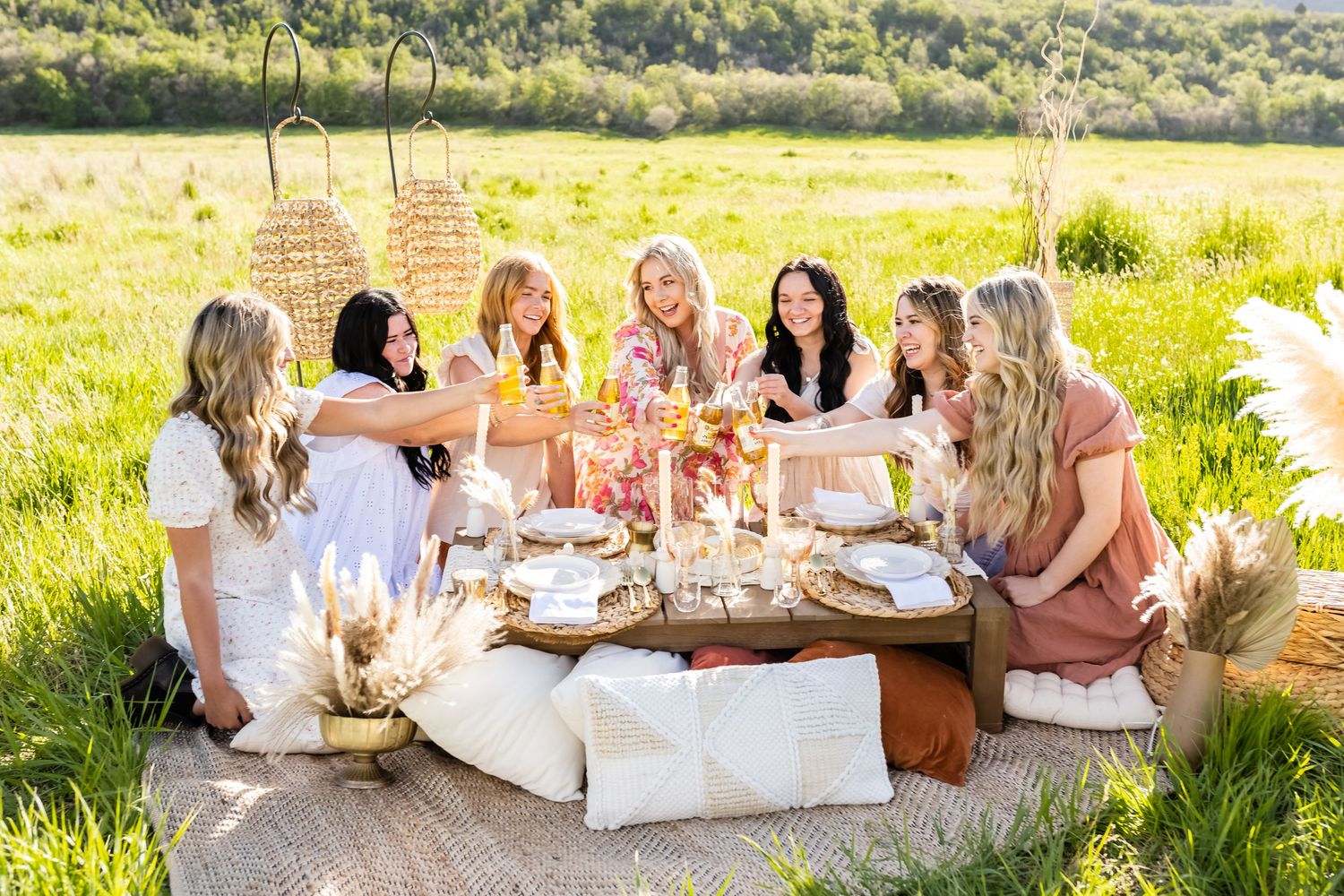 Group enjoying an elegant outdoor picnic setup with white tablecloths in a sunny meadow.