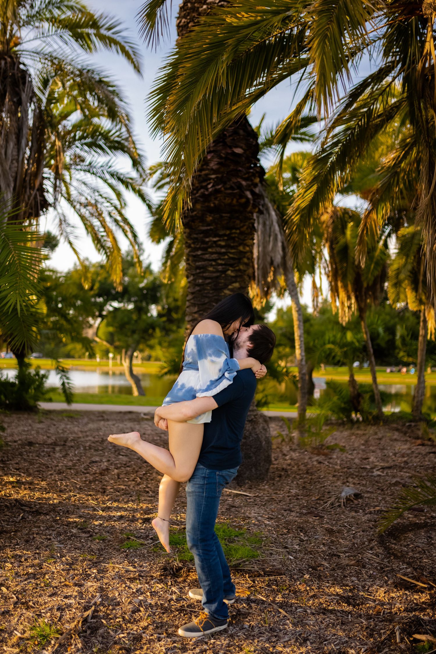 Romantic couple embracing under palm trees in a tropical garden setting.