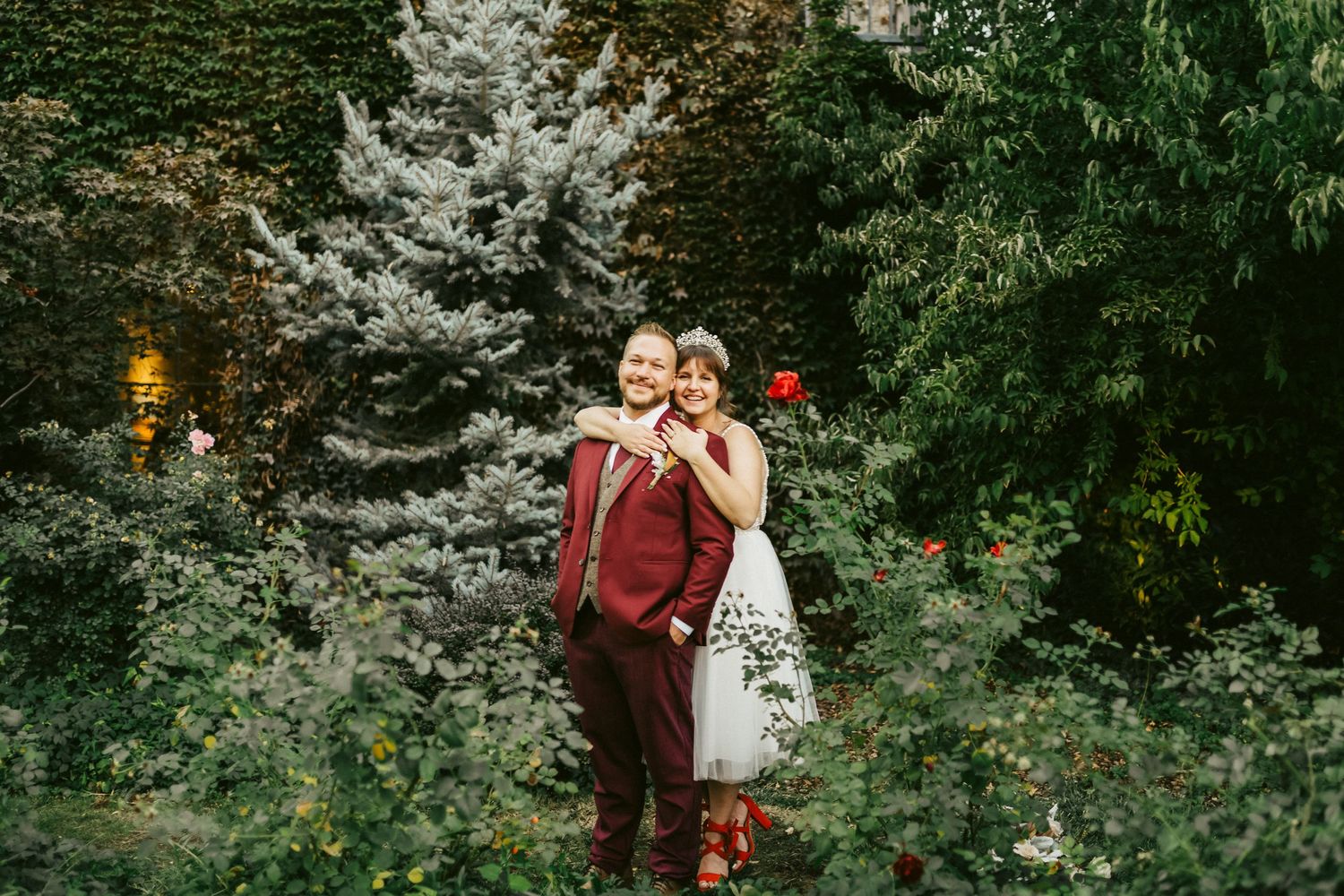 Wedding celebration in lush garden setting with illuminated trees at dusk.