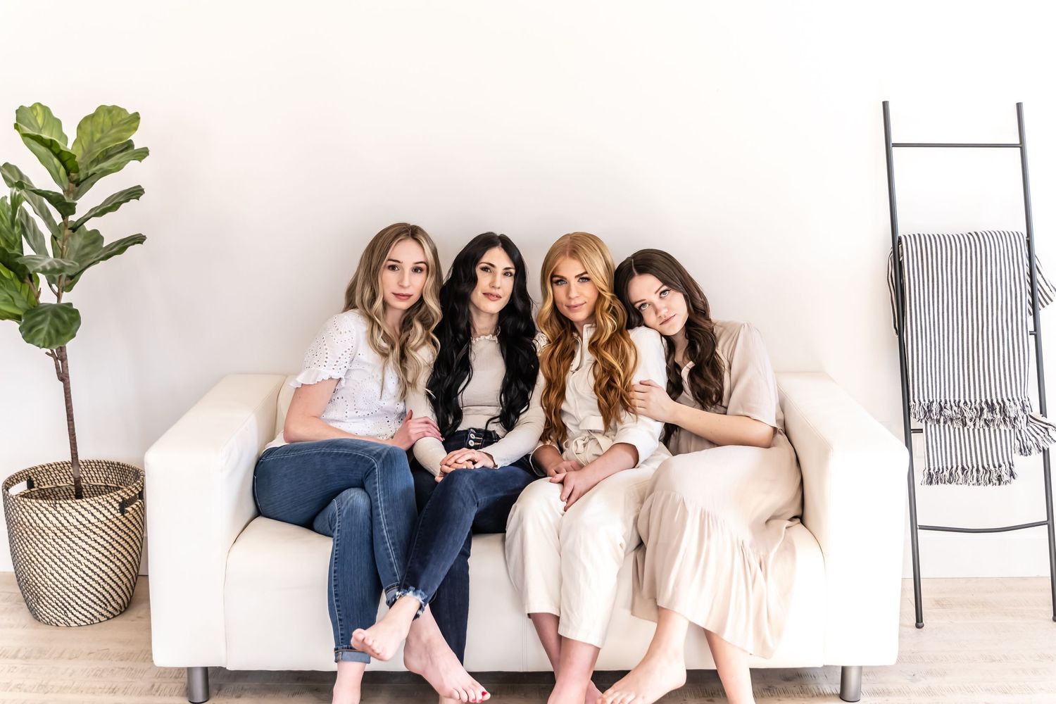 Friends relaxing together on white furniture in a modern minimalist indoor setting.