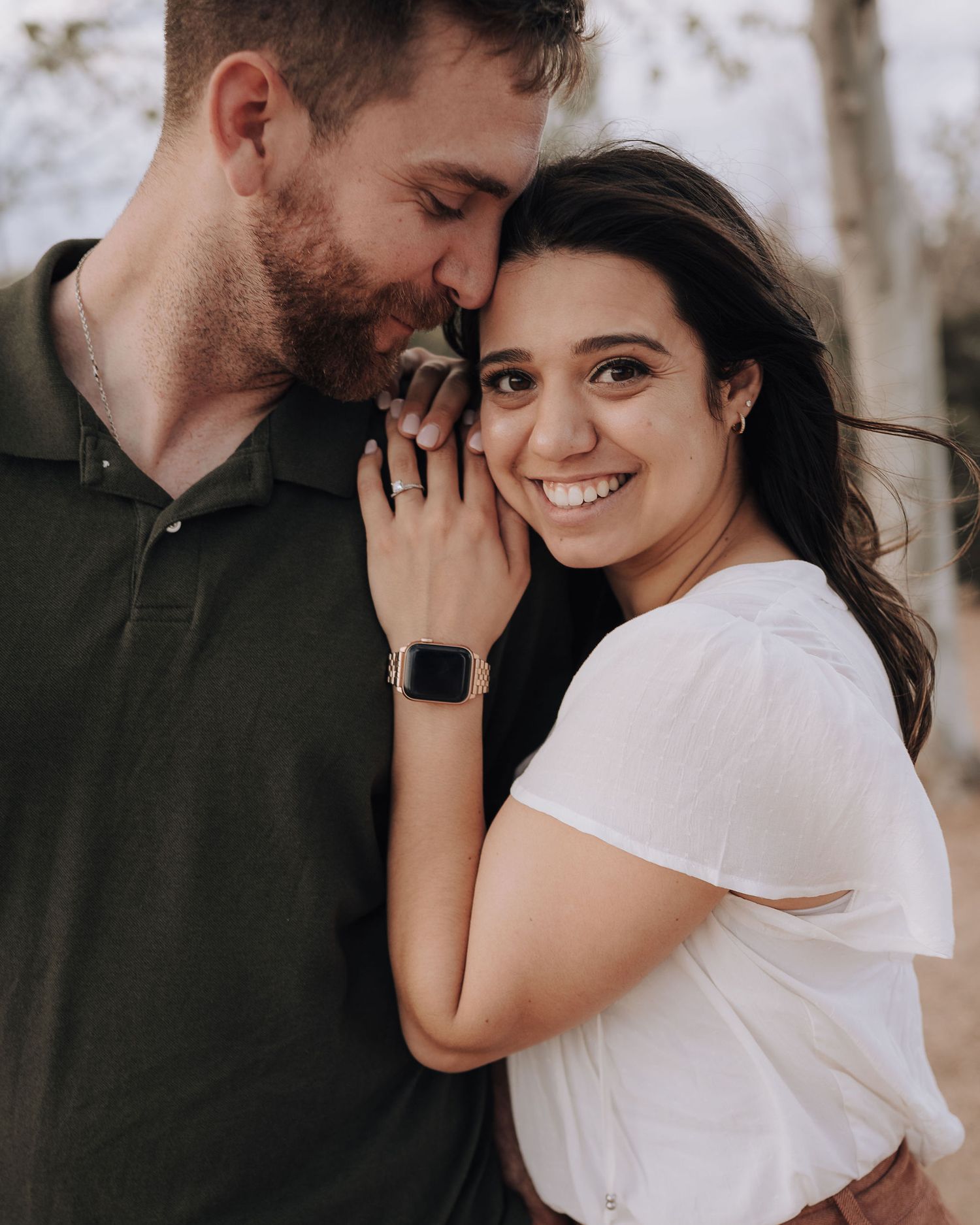A tender romantic moment captured between a couple in casual attire during an outdoor photoshoot.