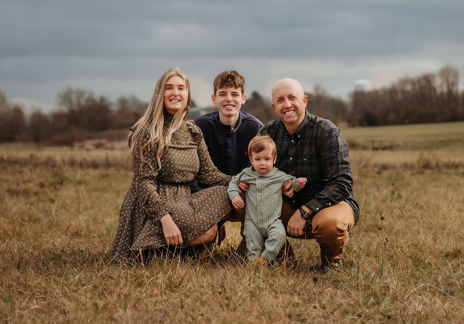 A family portrait taken in an open field during golden hour.