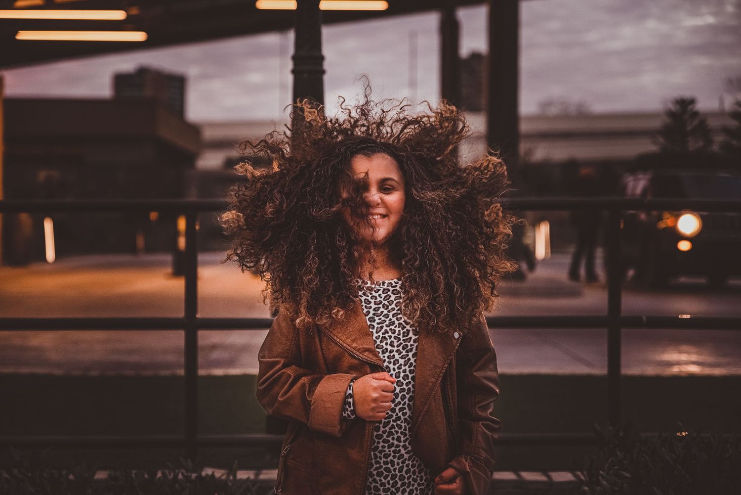 young smiling girl with big hair downtown