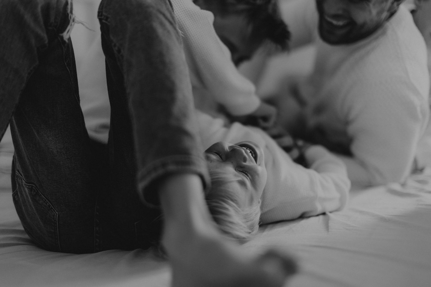 Black and white intimate family moment captured on bed.