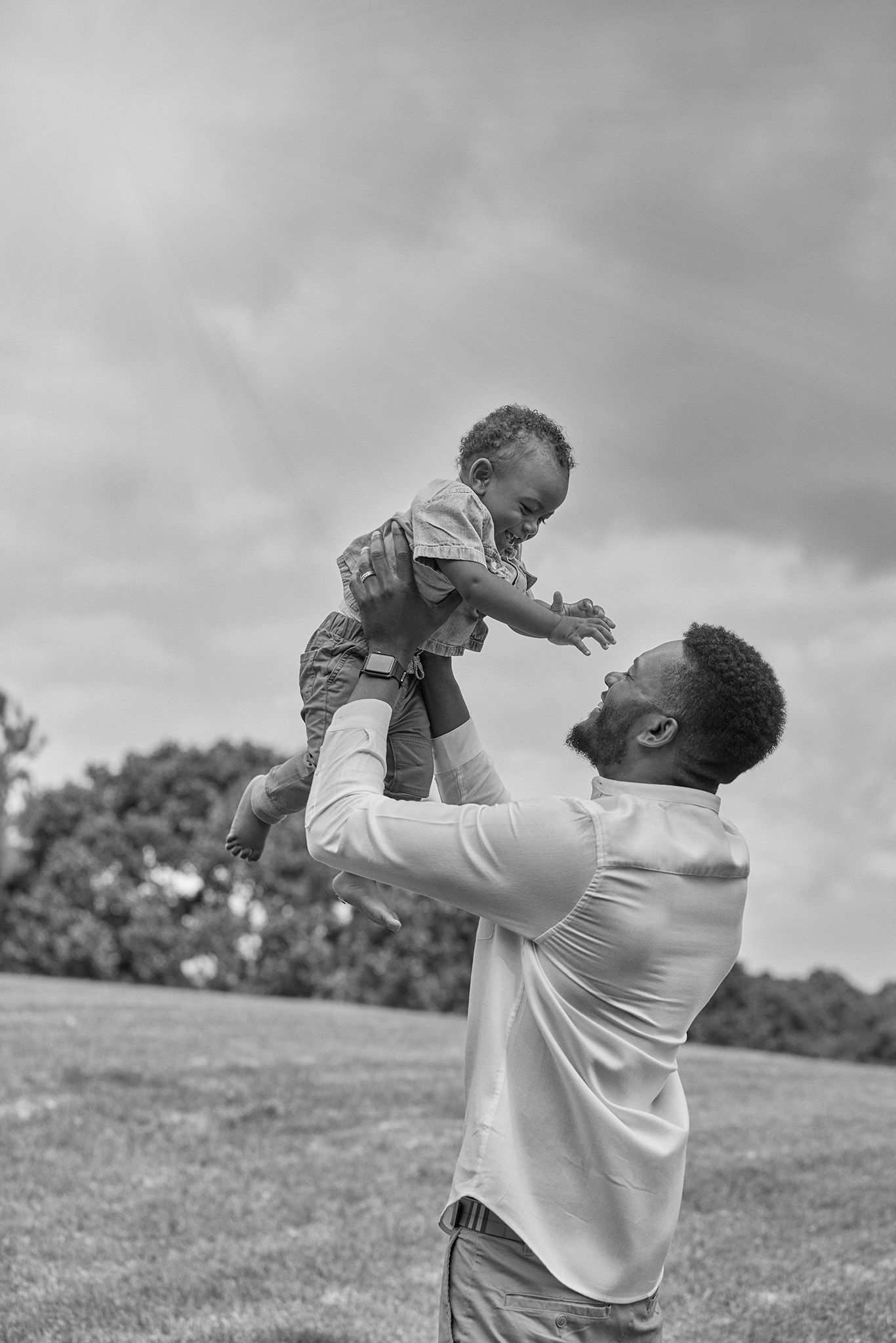 A joyful moment captured as a child is lifted high into the air outdoors.