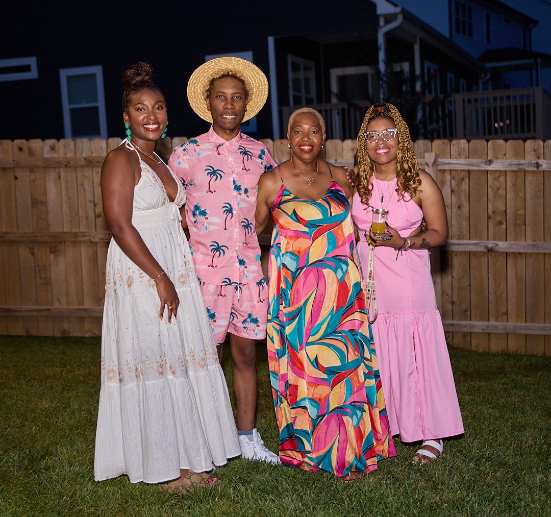 Group of friends in colorful summer dresses posing together at an outdoor evening gathering.