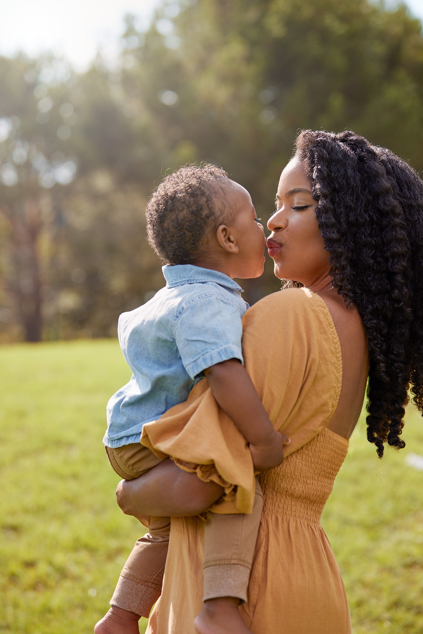 A tender moment shared between a parent and child outdoors in golden sunlight.