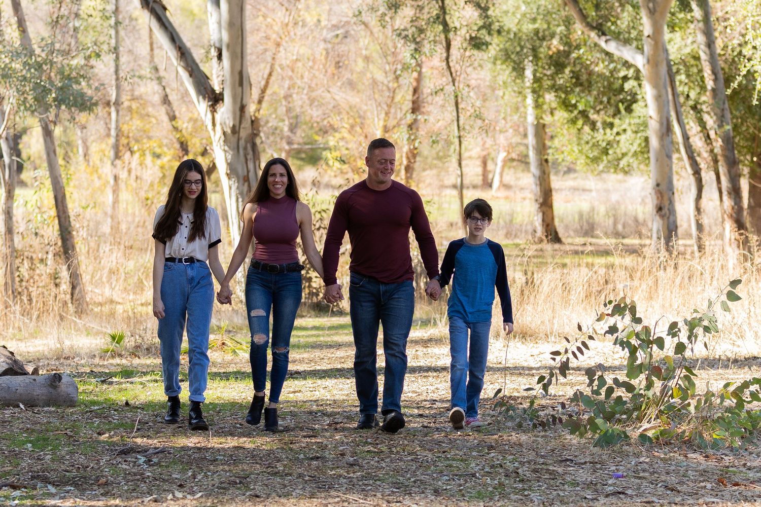 A family walks together along a tree-lined path during autumn.