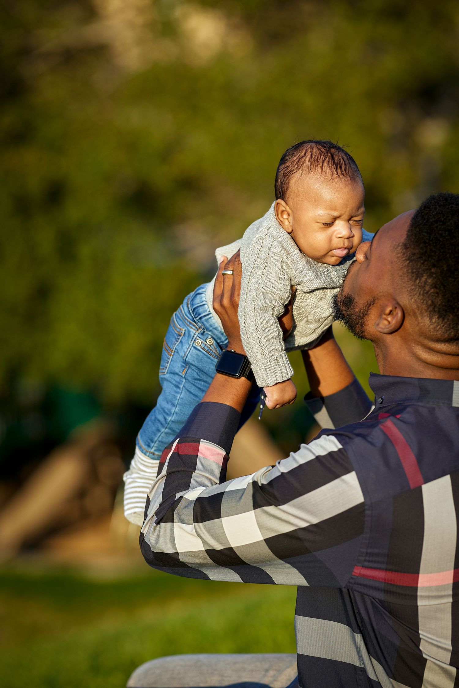 A tender moment between parent and baby in warm afternoon sunlight.