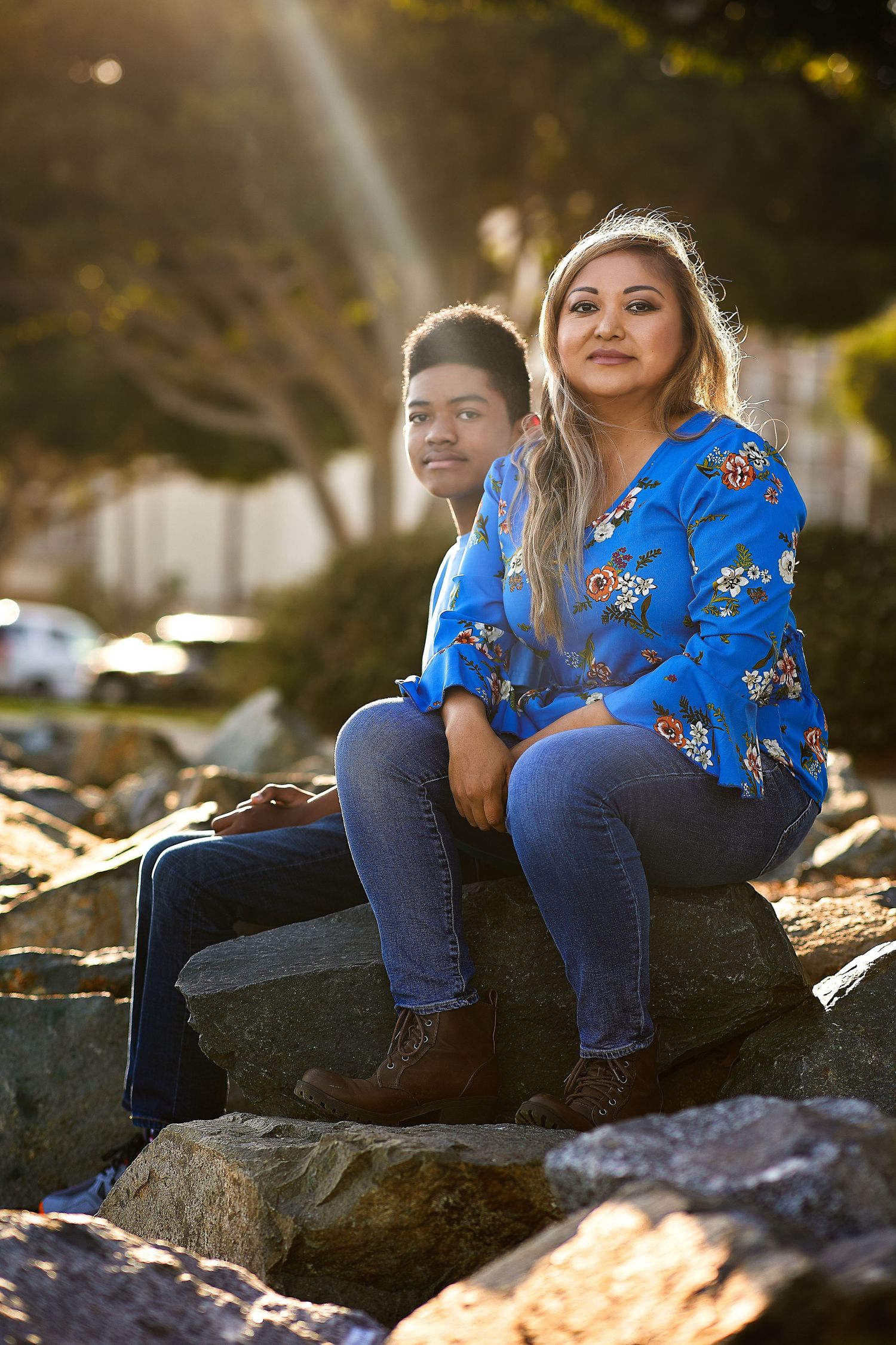 Two people relaxing together on coastal rocks during golden hour.