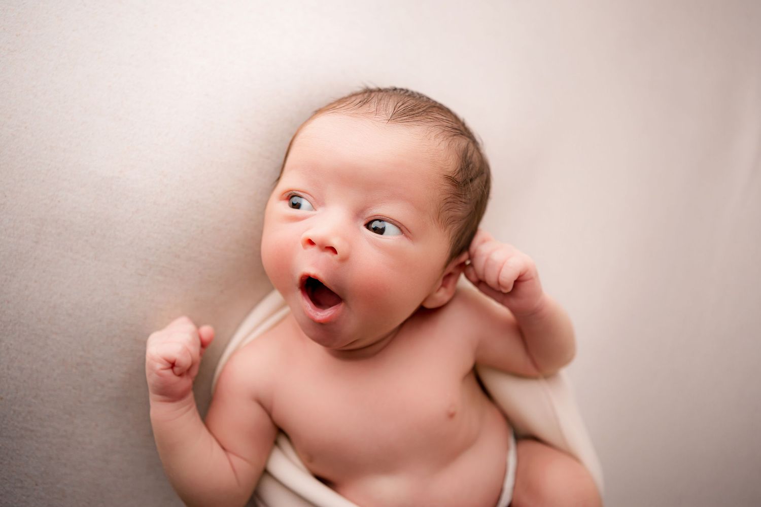 Baby boy yawning on white blanket in Flowertown Photography Studio in Summerville, SC