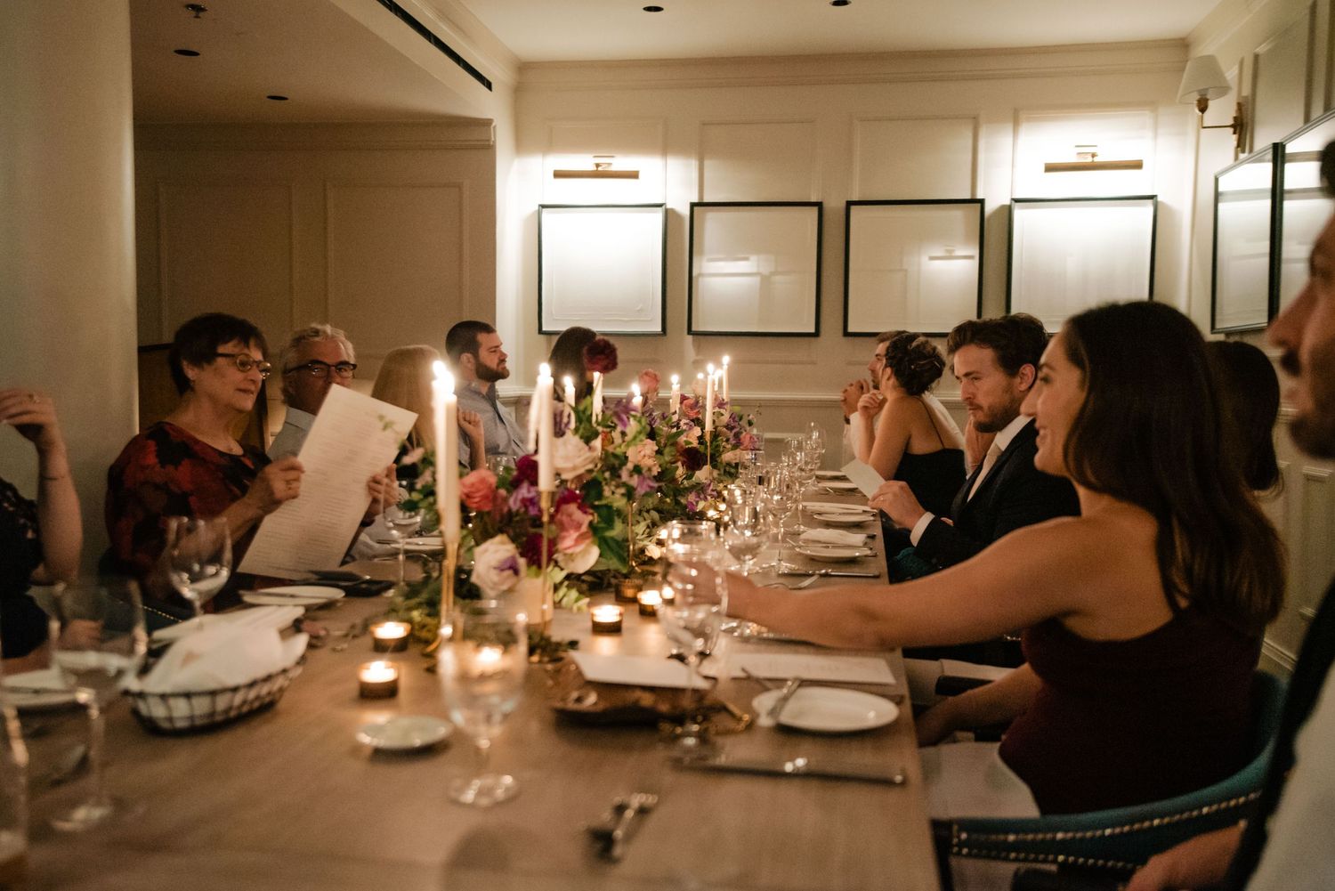 Candlelit dinner party scene with guests gathered around an elegantly set table.