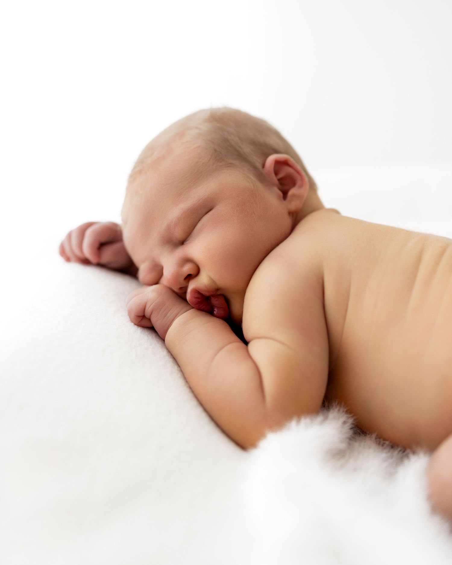 Peaceful sleeping newborn baby lying on white blanket in soft natural light at a studio in Adelaide, Australia,.