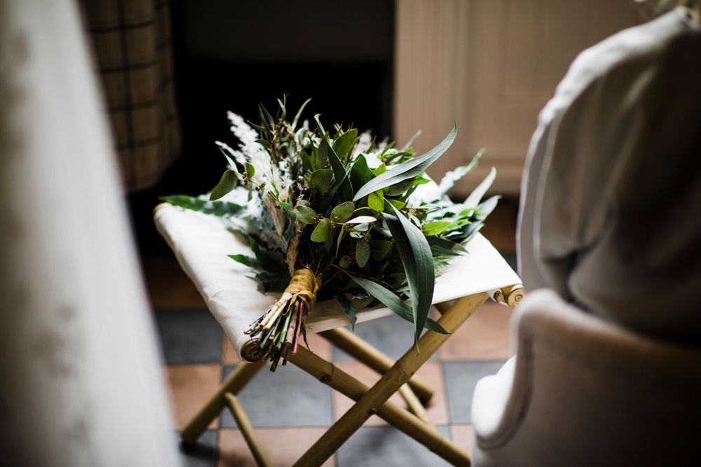Fresh green and white floral bouquet resting on a wooden folding chair.
