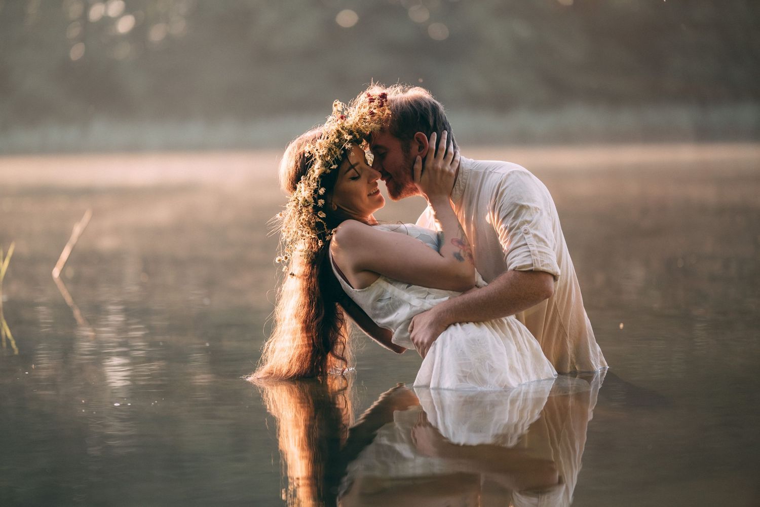 Golden sunlight illuminates romantic moment by misty lake.