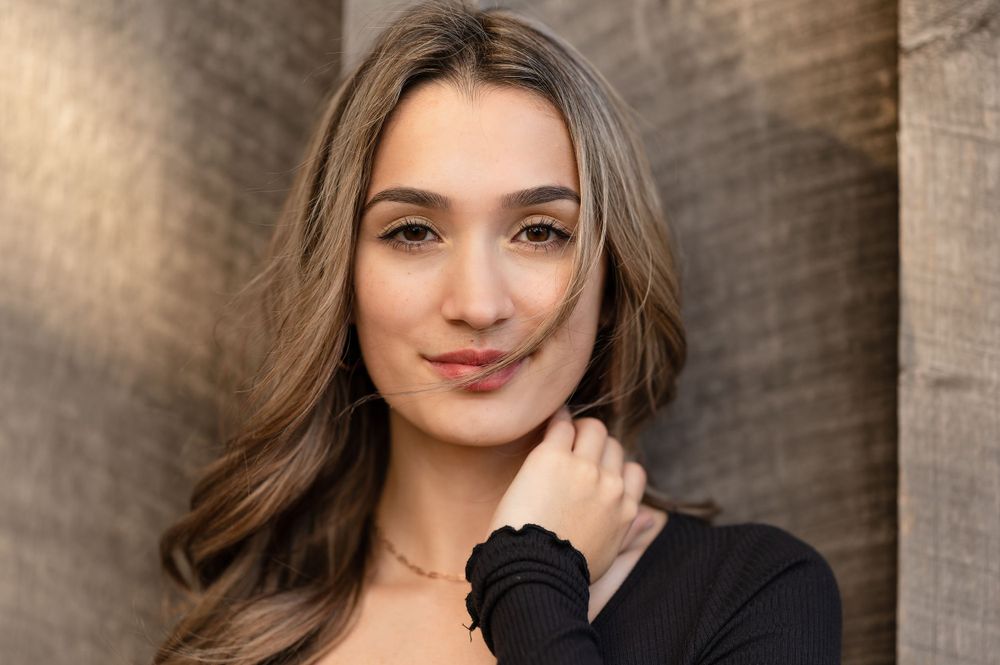 Professional headshot of a person in a black sweater against a textured background.