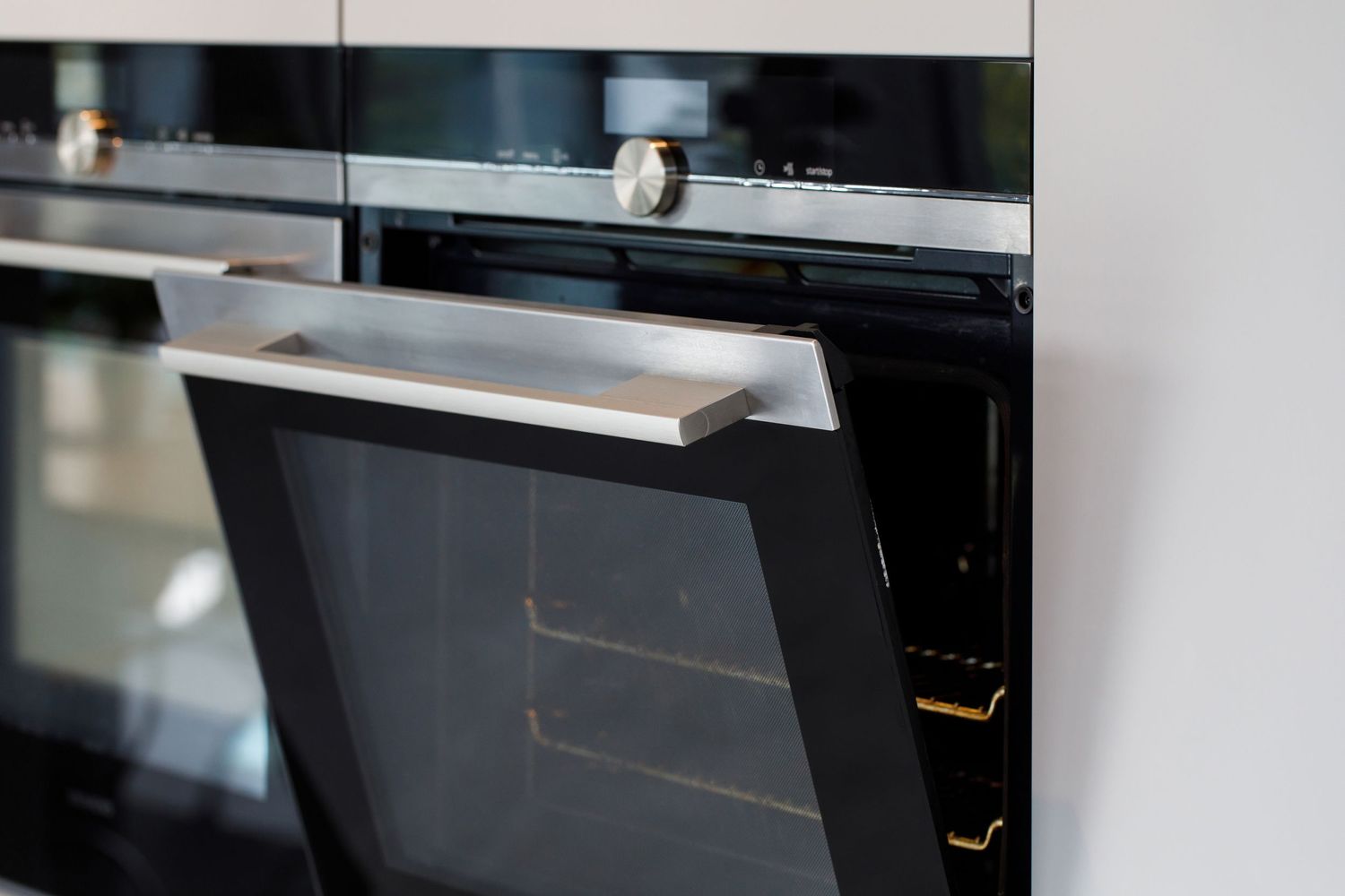 Close-up of modern built-in oven with sleek handle design in black and stainless steel finish taken during an interiors/kitchen photoshoot.