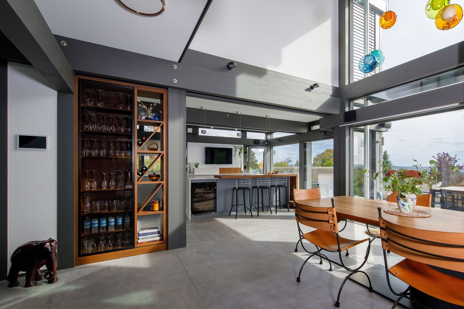 Contemporary open-plan living space with high ceilings, built-in shelving, and large windows offering natural light.