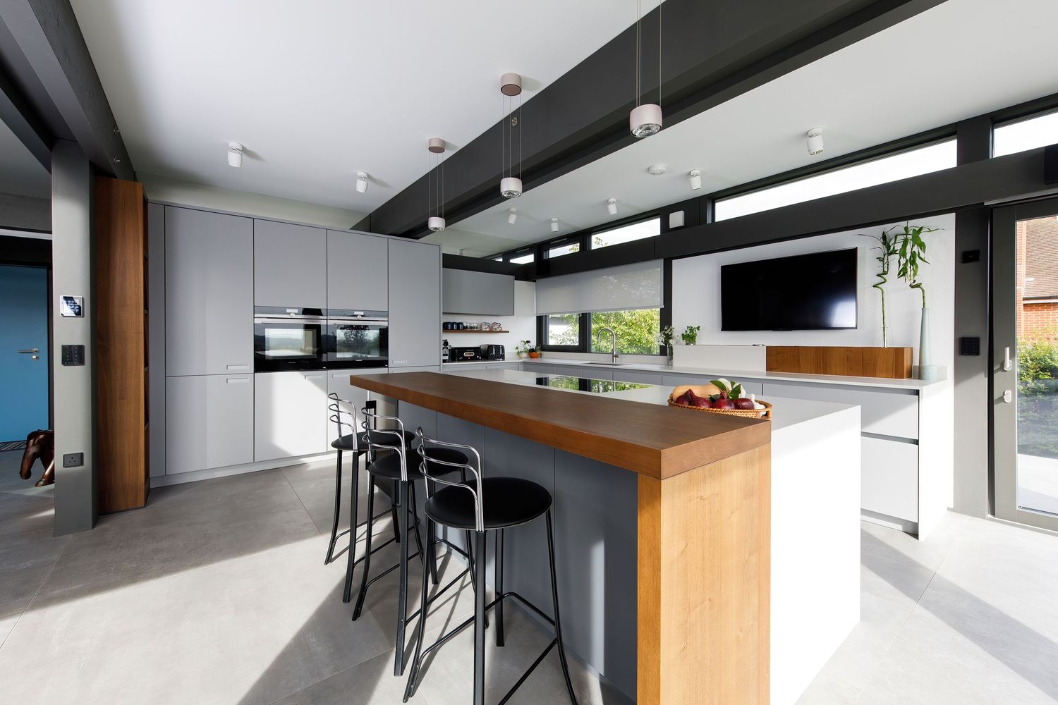Contemporary kitchen featuring wood and grey color scheme with central island and industrial lighting fixtures