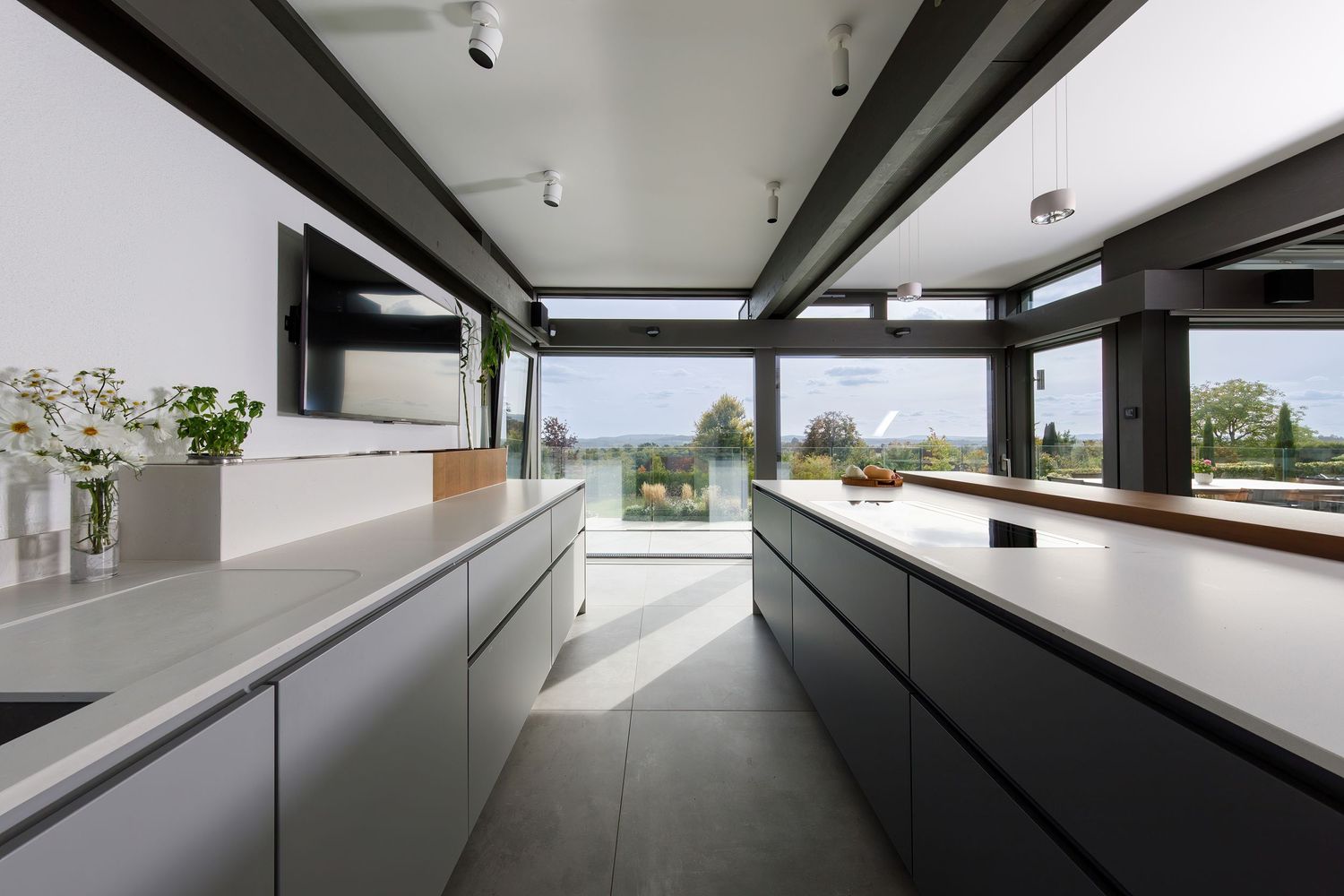 Minimalist kitchen design with handleless cabinets, long countertops and panoramic windows overlooking nature