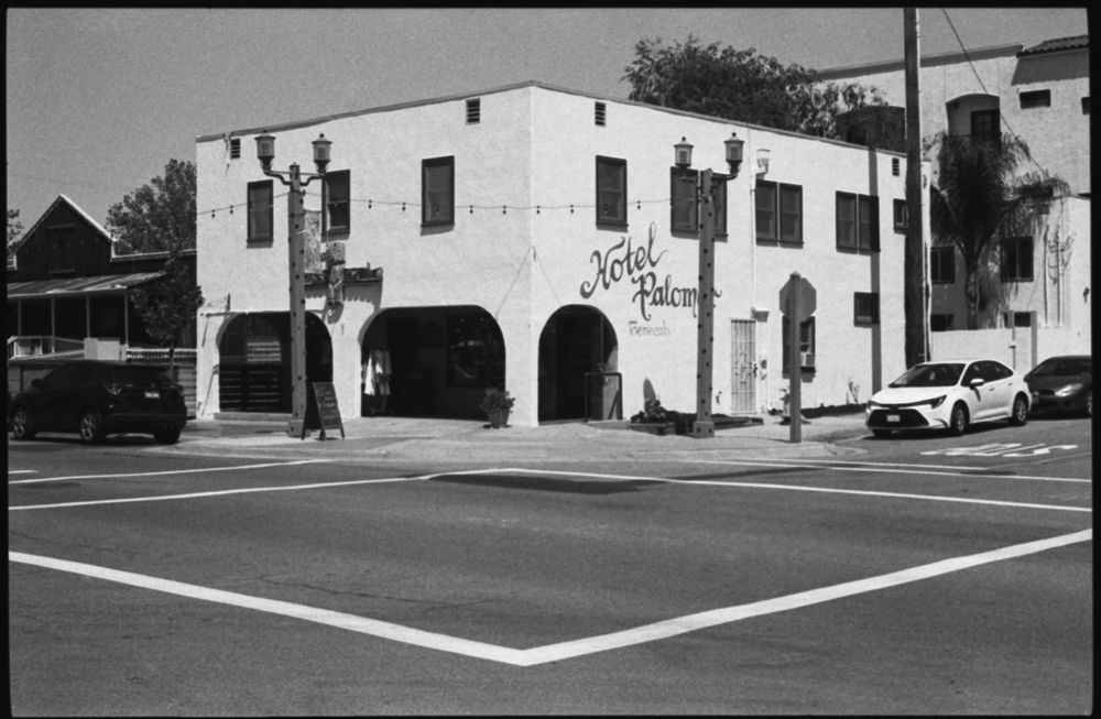 Vintage white Spanish colonial style building with arched entryways on a street corner.
