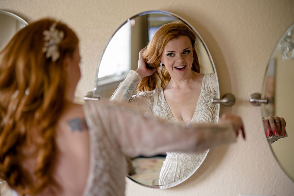 A reflection in a round mirror showing wedding day preparations.
