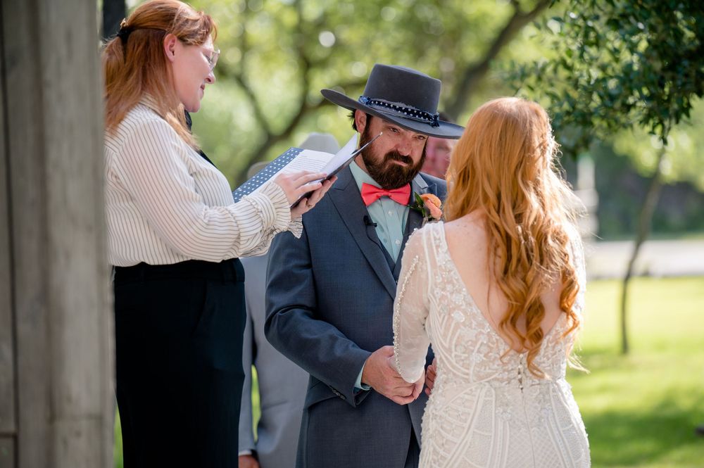 Wedding ceremony taking place outdoors with officiant and couple.