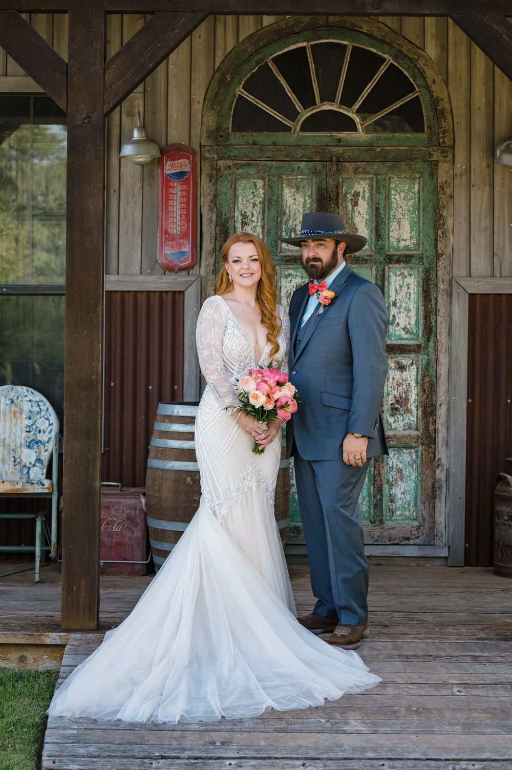 A rustic wedding portrait in front of a weathered green door with vintage decor elements.