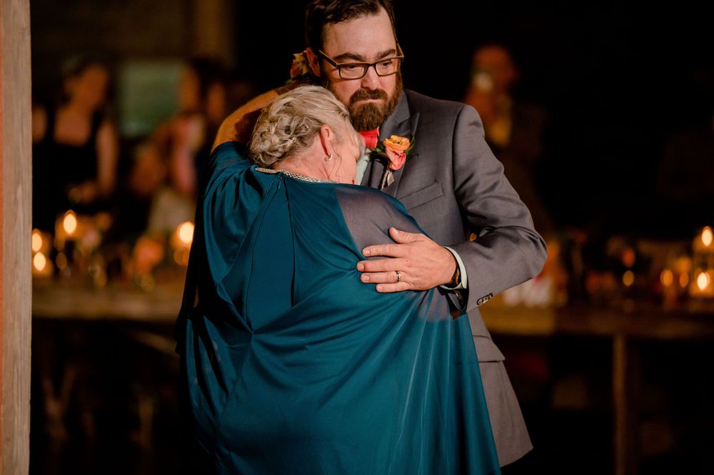 An emotional dance moment captured during a wedding reception in dimly lit venue.