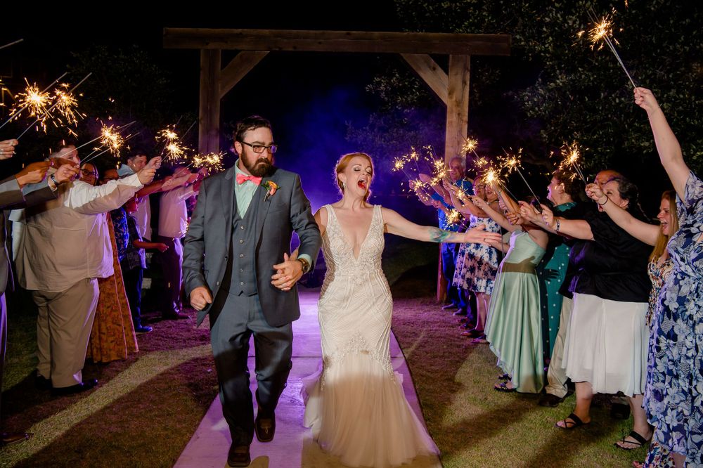 Joyful wedding exit with guests holding sparklers creating magical nighttime atmosphere.