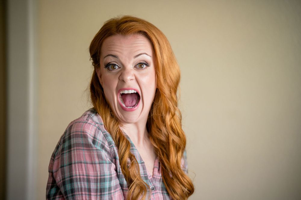 Portrait showing excited expression with vibrant red hair.