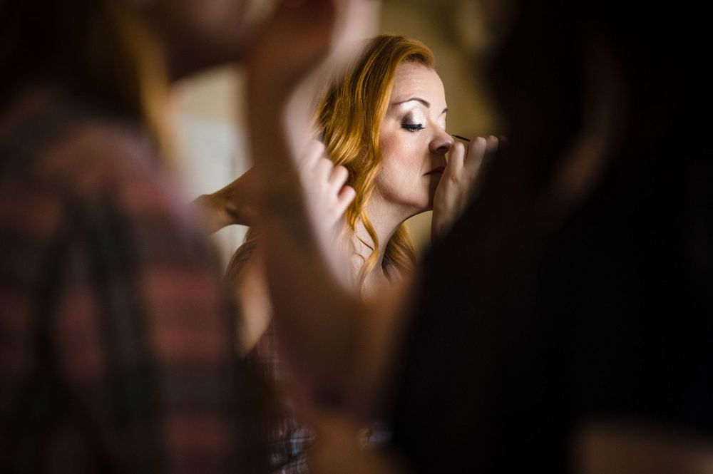 Artistic side profile shot of someone getting makeup applied in soft lighting.