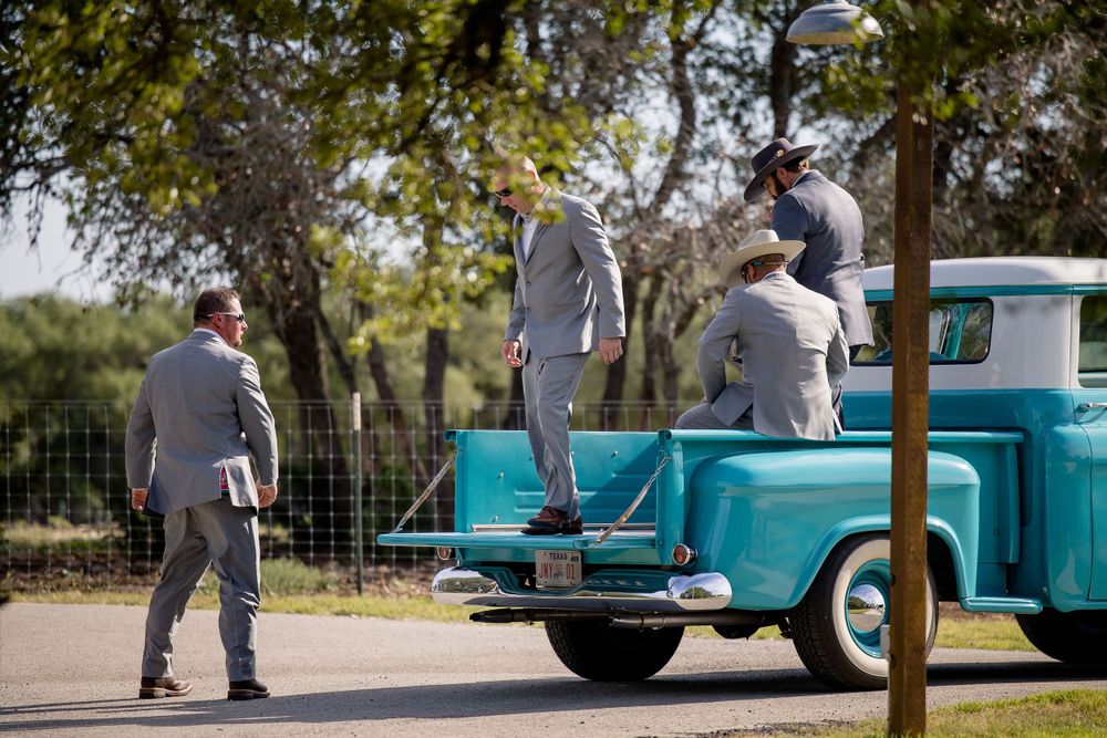 People gathering around a classic turquoise pickup truck at an outdoor event.