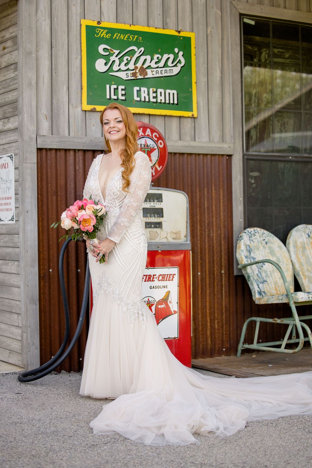 A bride poses in a lace wedding dress in front of a vintage ice cream shop sign and retro Coca-Cola machine.