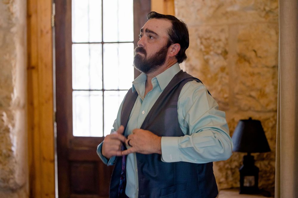 Getting ready scene with formal attire in rustic wooden room with natural window light.
