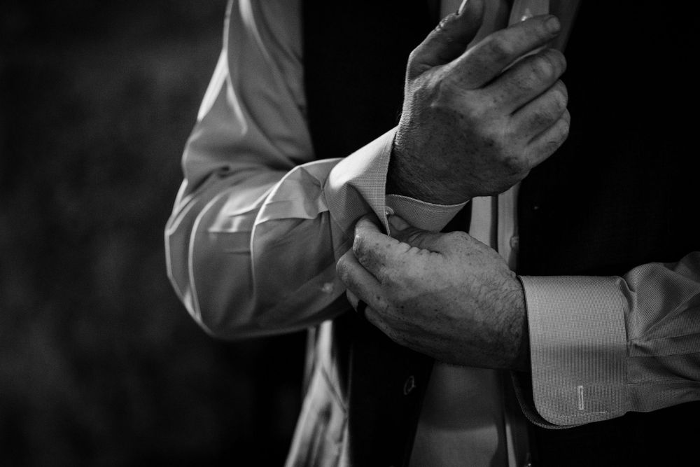 Black and white detail shot of hands adjusting formal wear cufflinks.