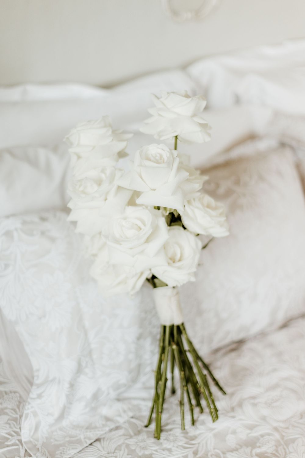Fresh white rose bouquet lying on white textured fabric.
