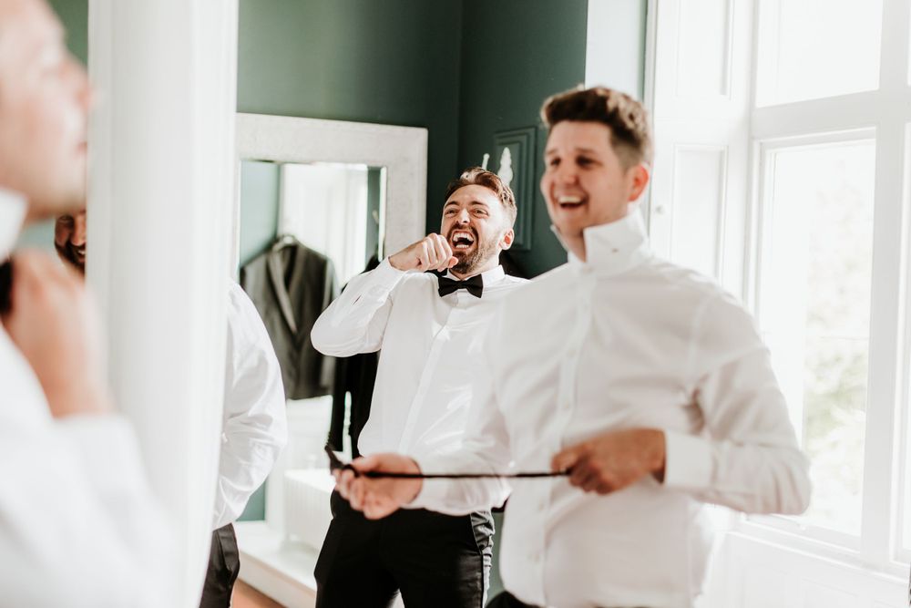 Wedding party members sharing laughter while getting ready in bright room.