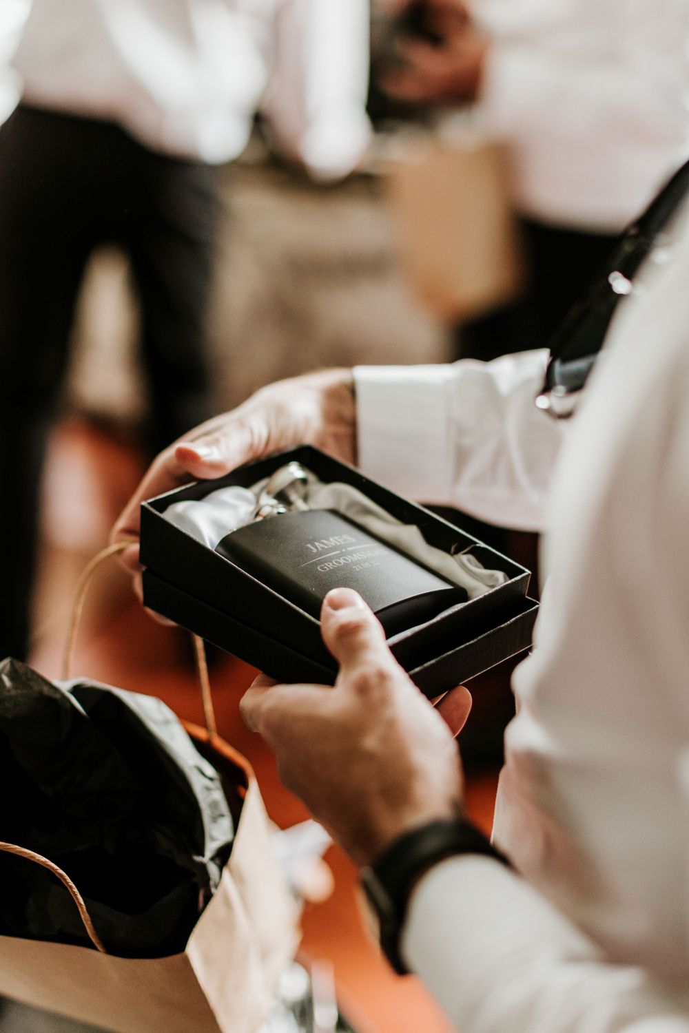Hands opening a black gift box containing a special present during wedding preparations.