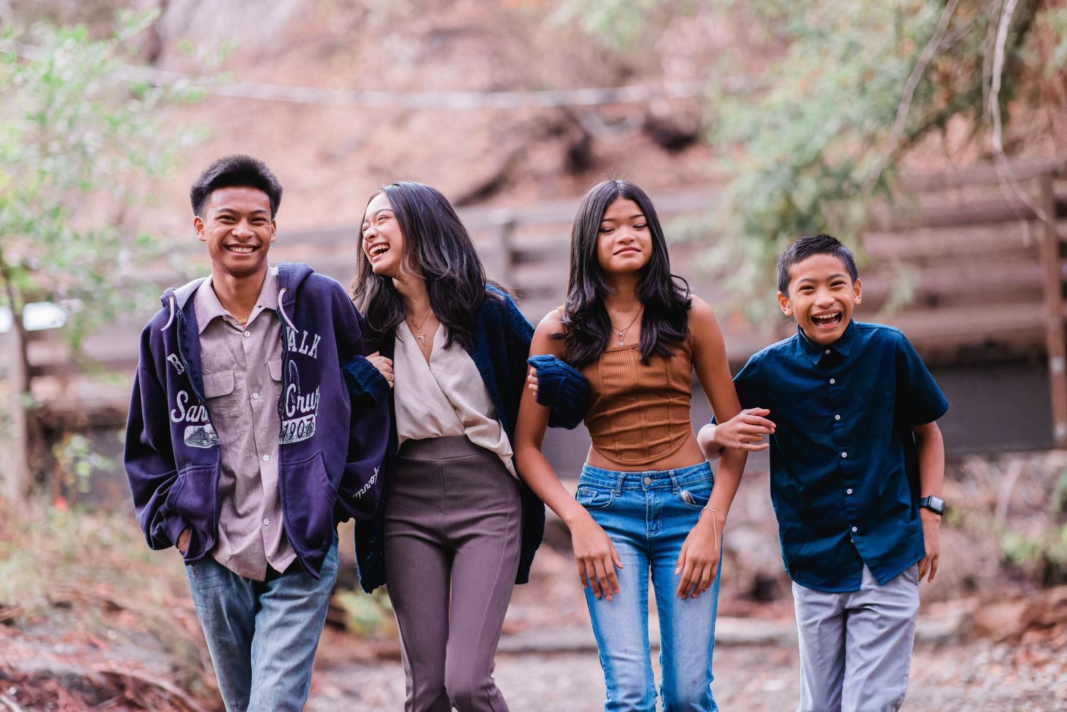 Group walking and laughing together on forest trail with red rock formations in background.