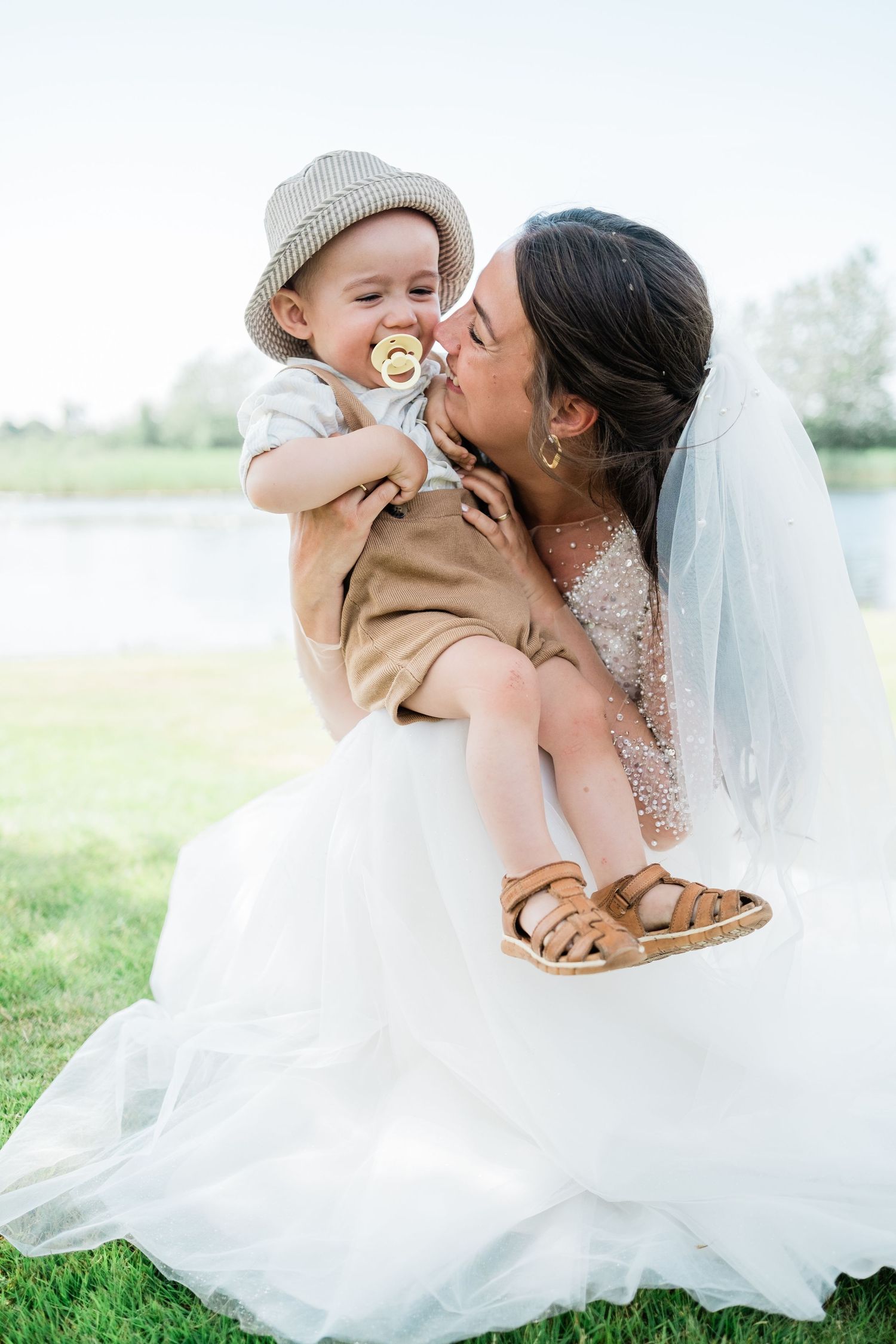 A sweet moment between a bride in a sparkly dress and a small child wearing a sun hat.