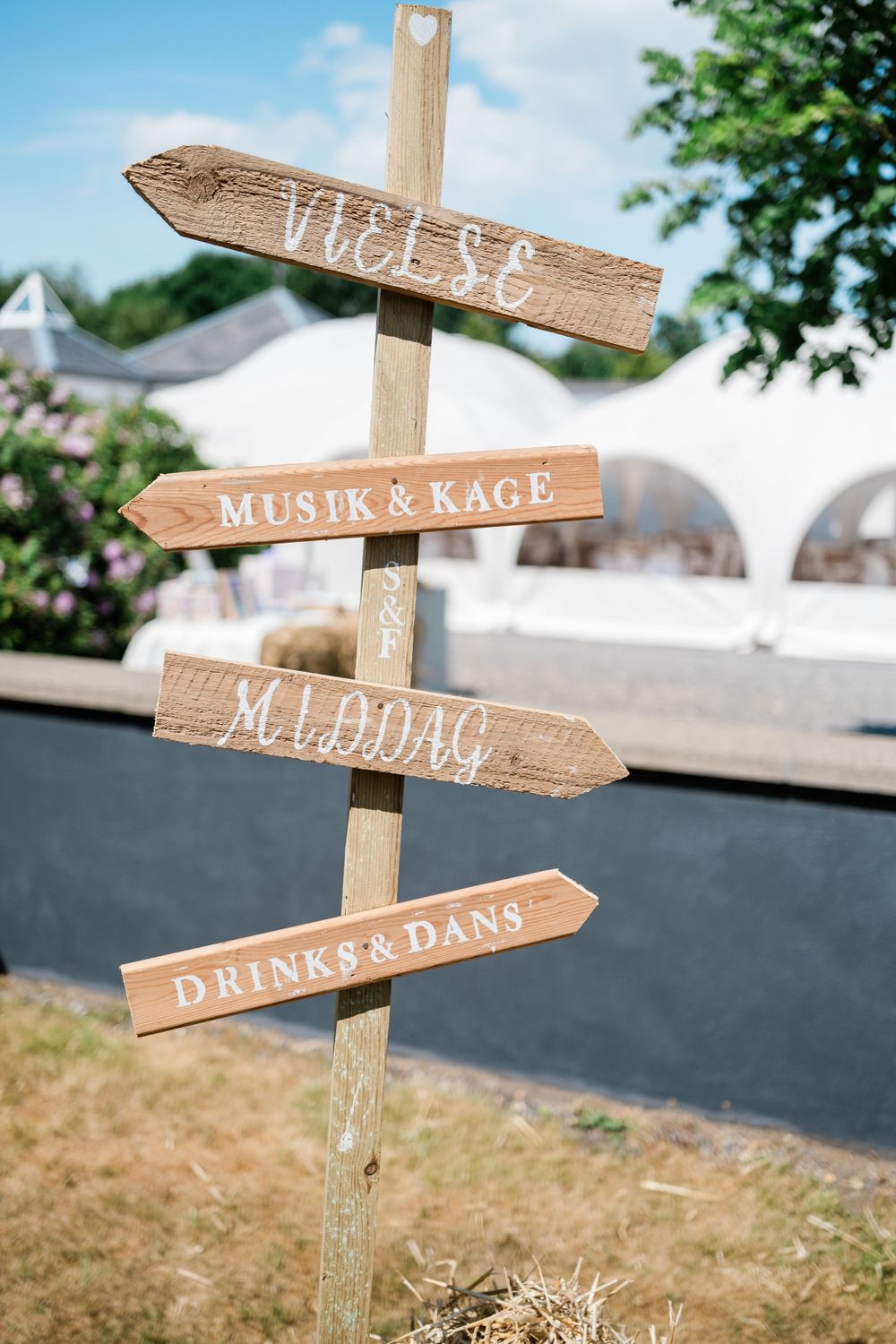 Rustic wooden directional signs at a wedding pointing to various activities and areas.