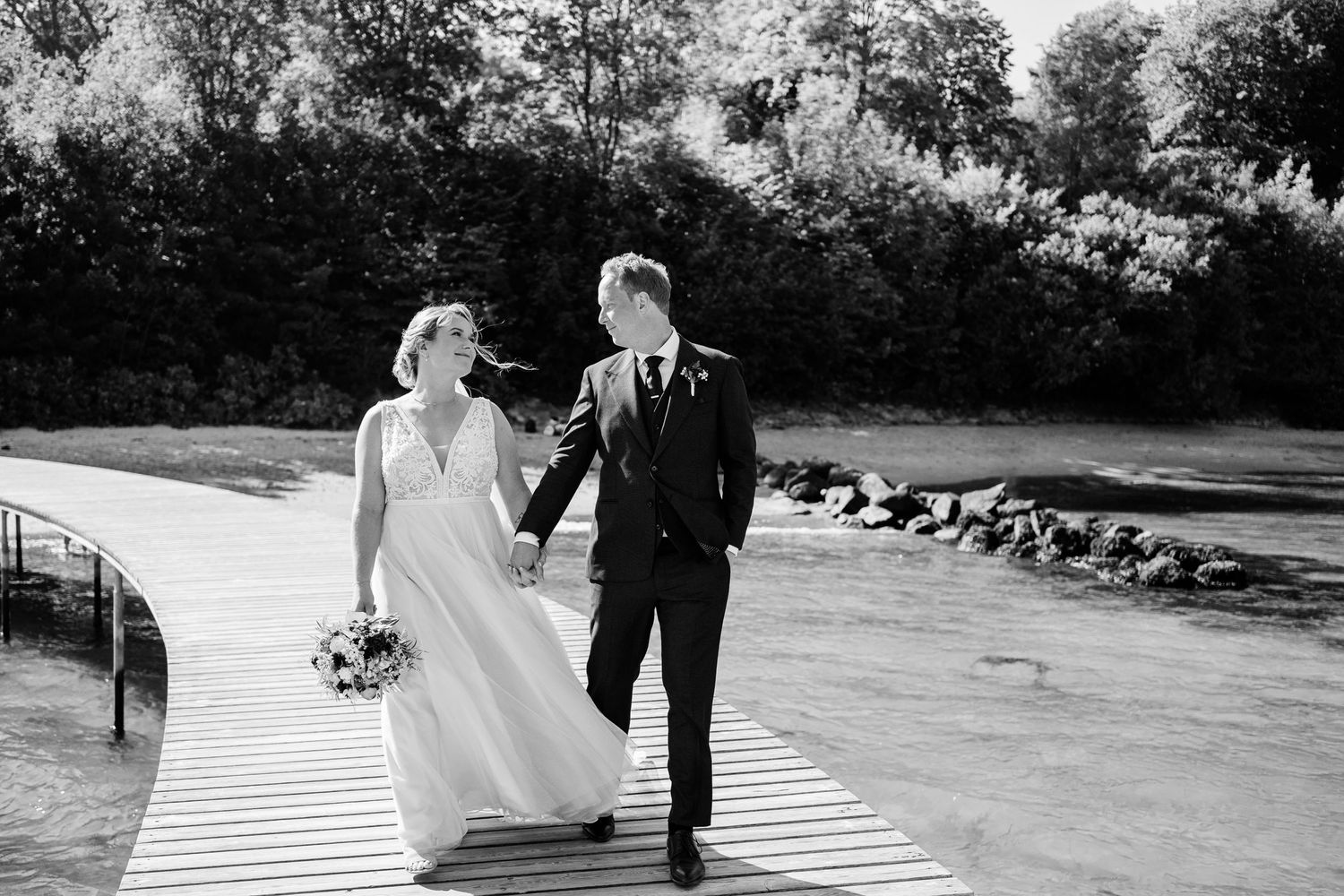 Black and white photo of couple walking together on curved boardwalk.