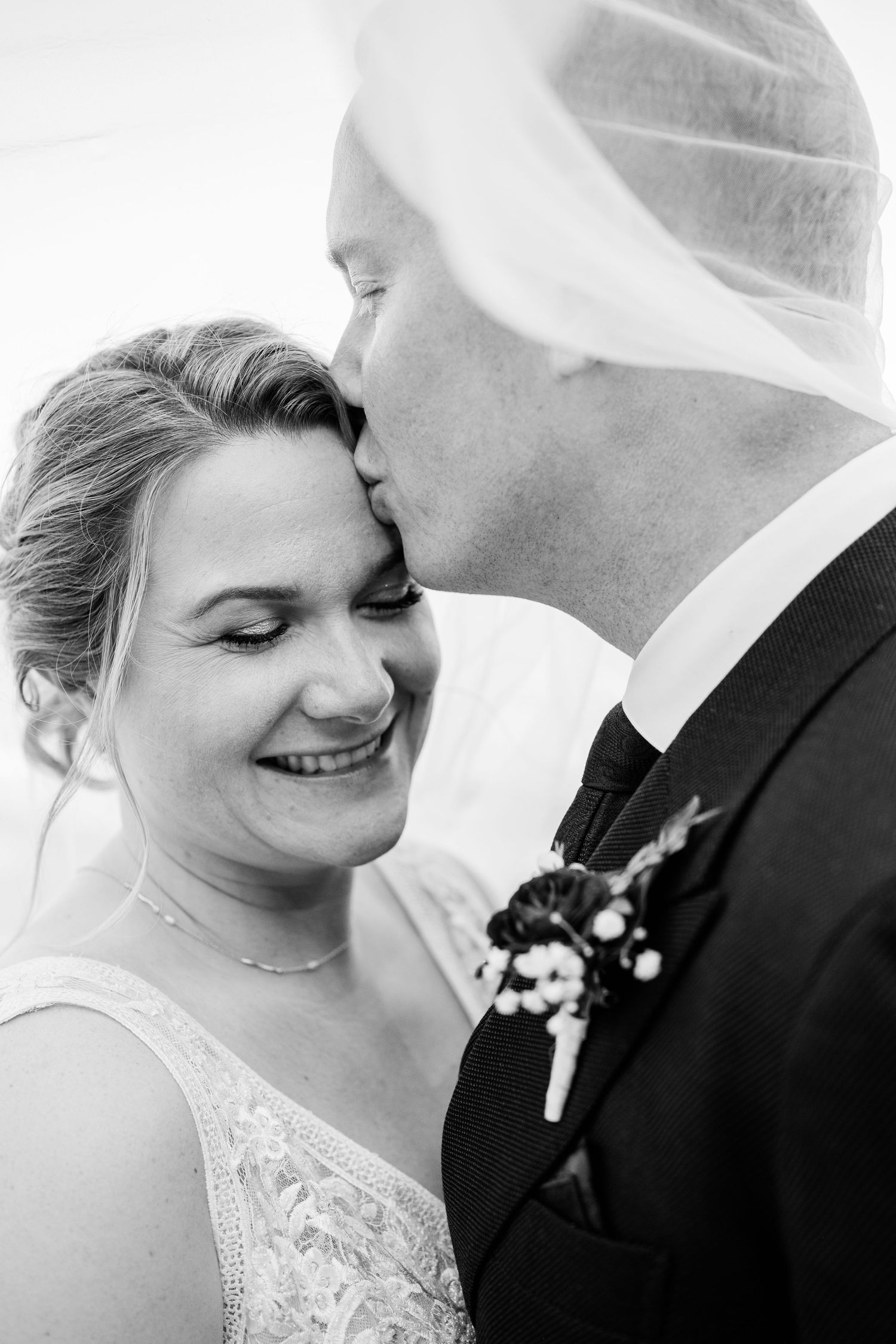 A tender black and white wedding moment captured between a couple wearing traditional wedding attire.