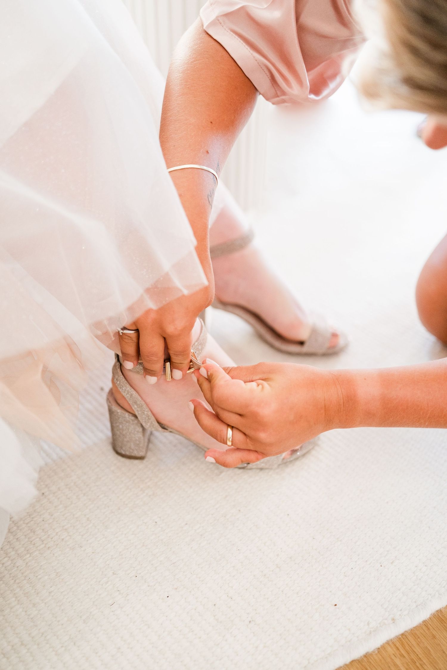 Close-up of hands fastening wedding shoe strap on carpet.