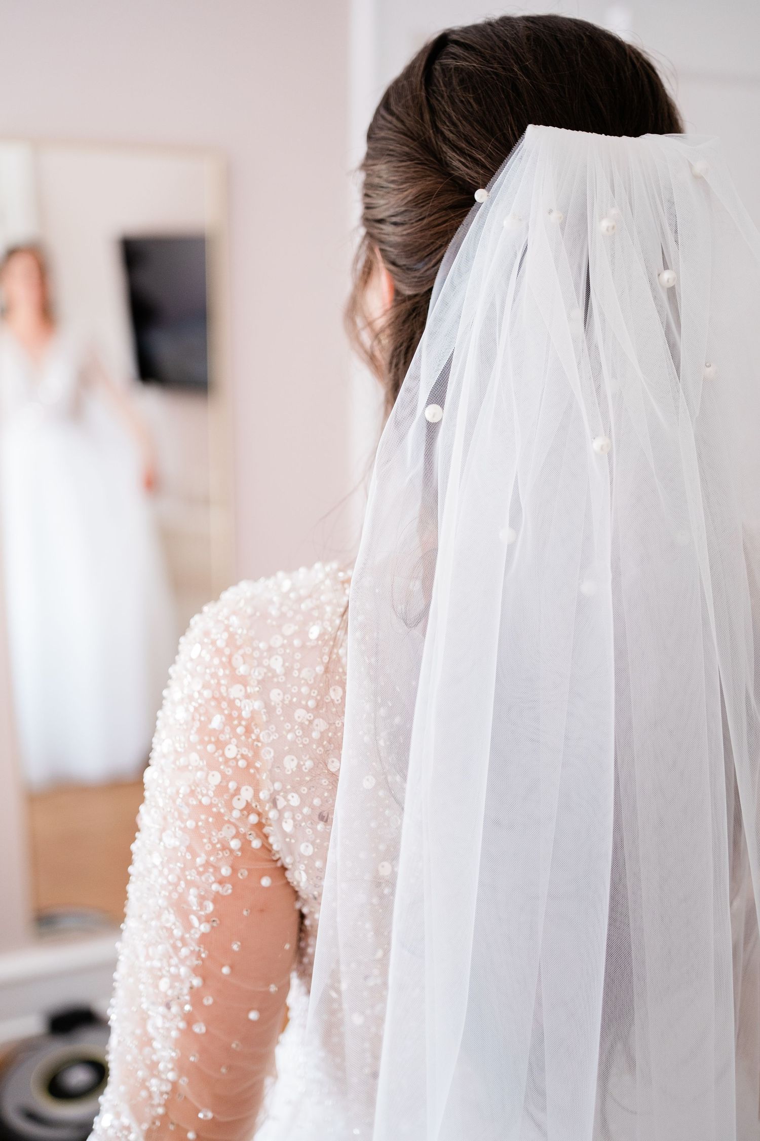 Detail shot of a delicate white wedding veil and beaded dress.