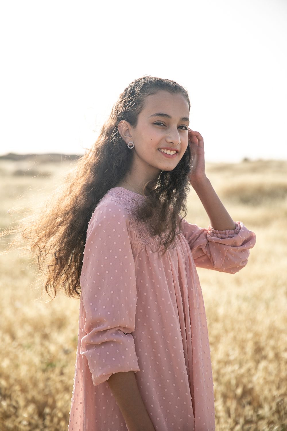 Portrait of a girl standing and smiling in a golden field