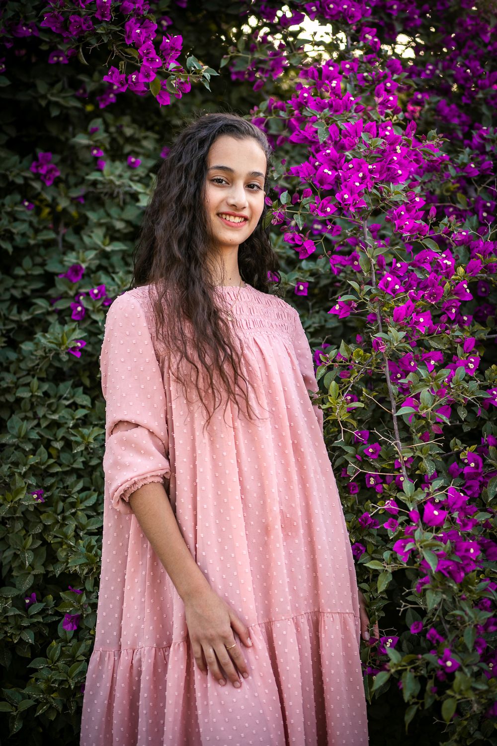 A smiling girl with purple flowers in the background