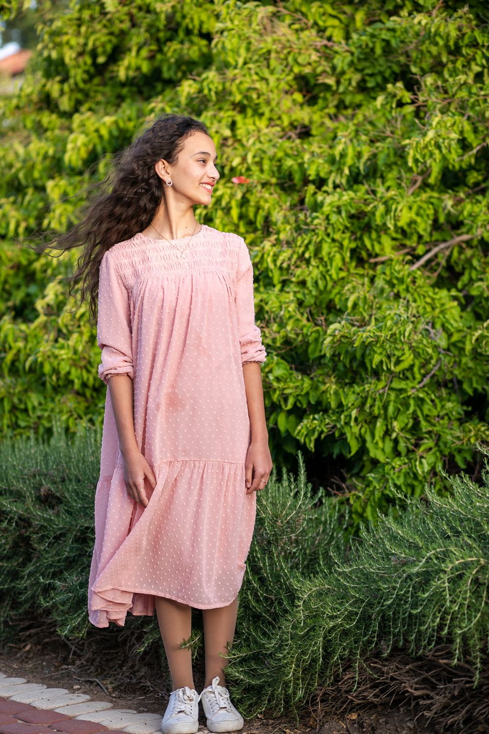 A girl in a pink dress stands and looks aside